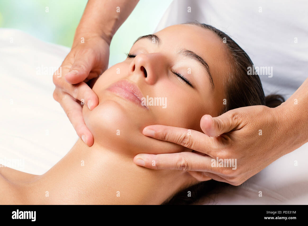 Close up facial massage on female chin.Therapist applying revitalizing cream on face. Stock Photo