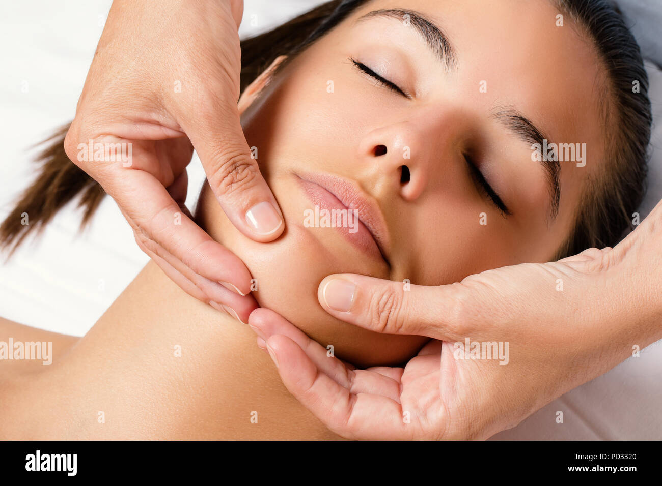Close up top view portrait of woman at beauty treatment session. Therapist applying cream on chin. Stock Photo