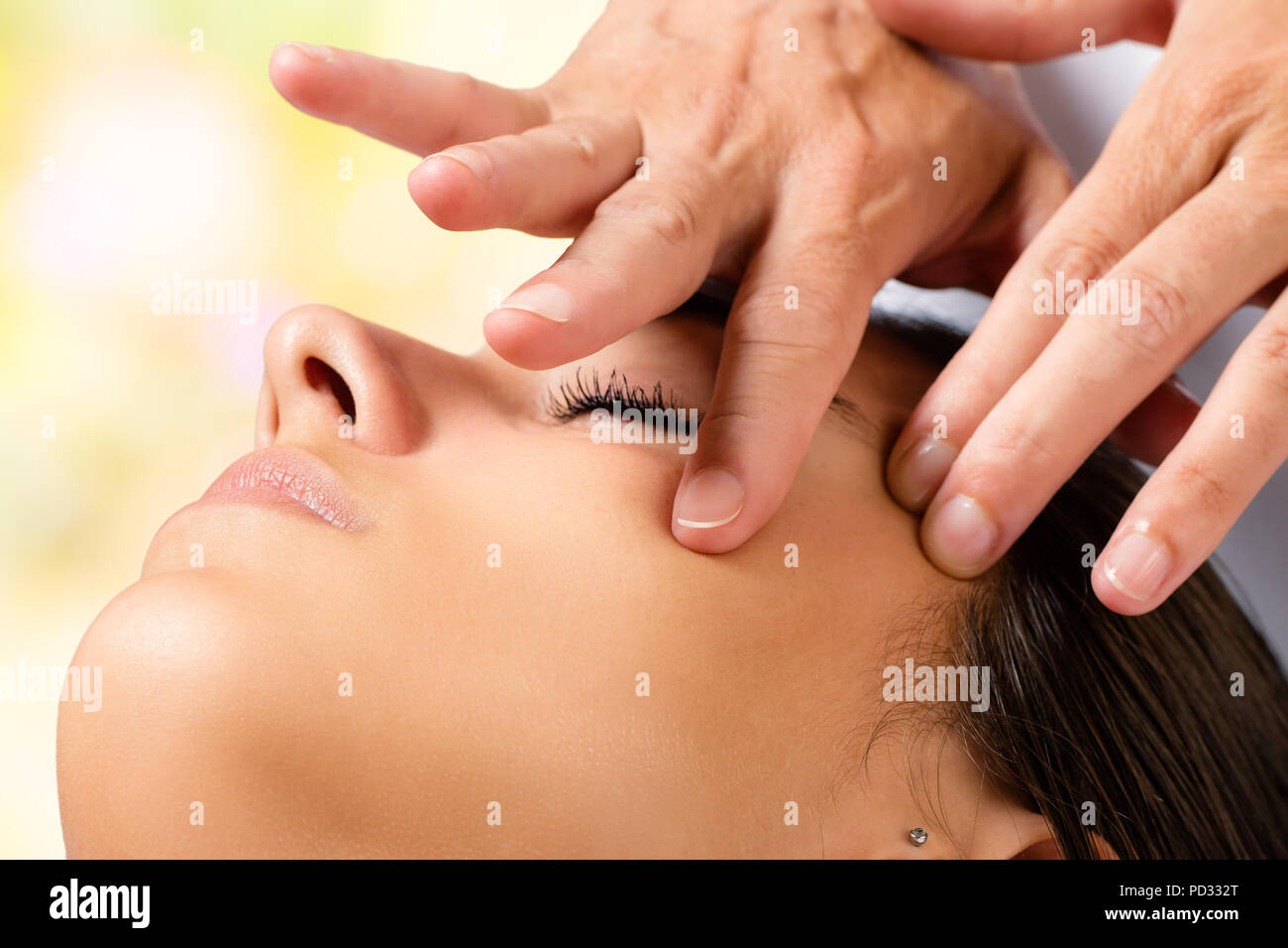Extreme close up portrait of woman having beauty facial treatment. Therapist doing massage with product on cheek. Stock Photo