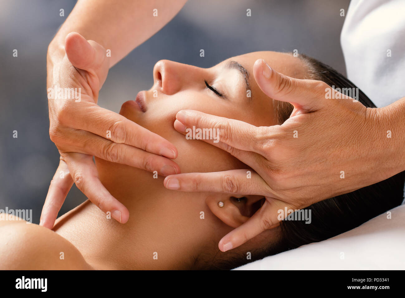 Close up portrait of woman having facial cosmetic therapy. Therapist applying cream on female cheek. Stock Photo