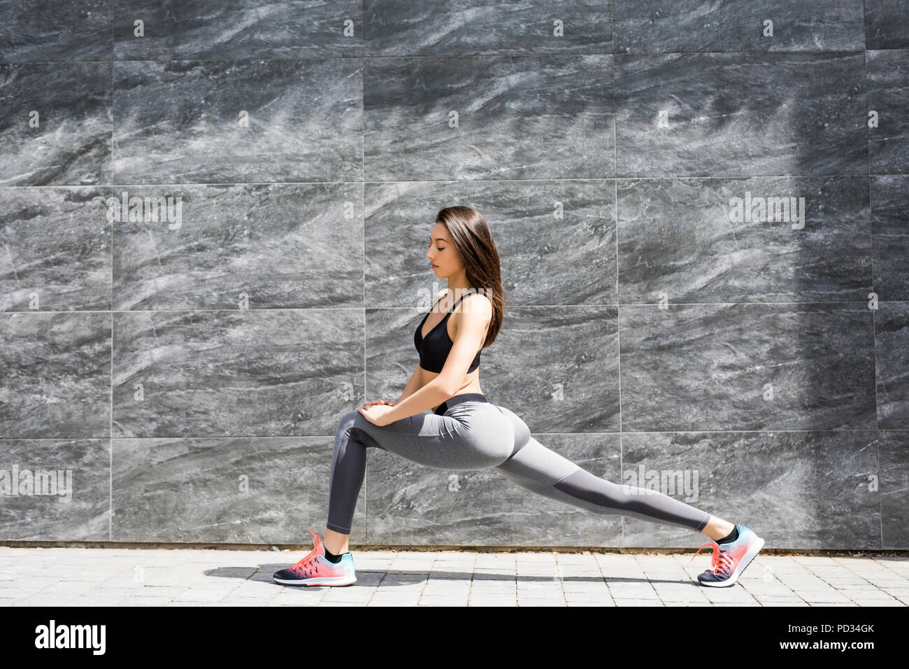 Stylish attractive young female runner in black sportswear doing warm ...