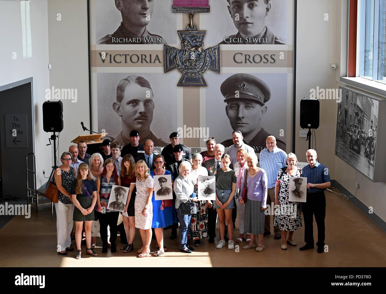 Bovington, UK. 6th August 2018. For the first time in history the four Victoria Crosses awarded to tank crews in the First World War are being brought together at The Tank Museum in Bovington, Dorset Family members hold pictures of their relatives Credit: Finnbarr Webster/Alamy Live News Stock Photo