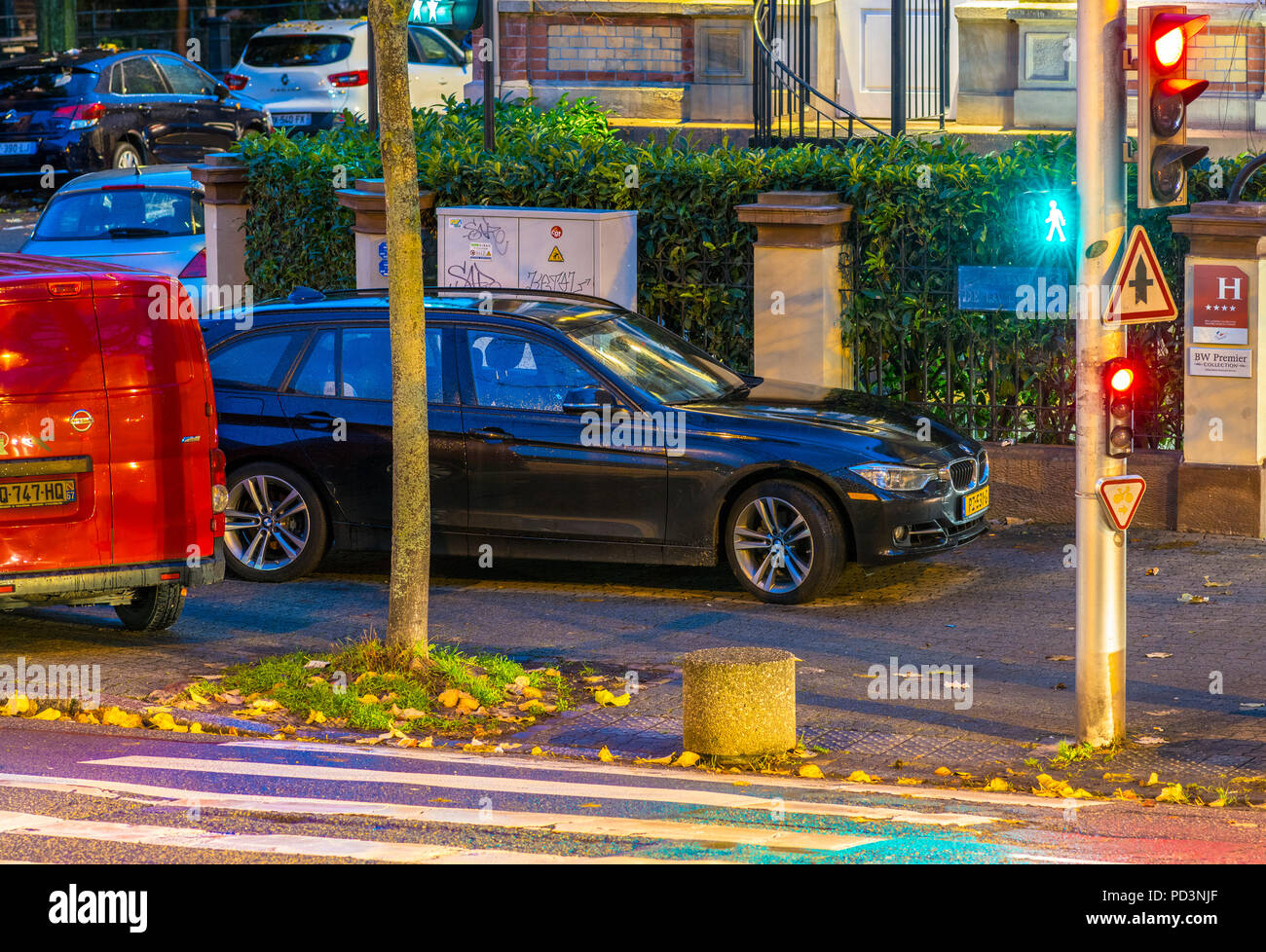 Cars parked on pavement at night, pedestrian crossing, traffic lights
