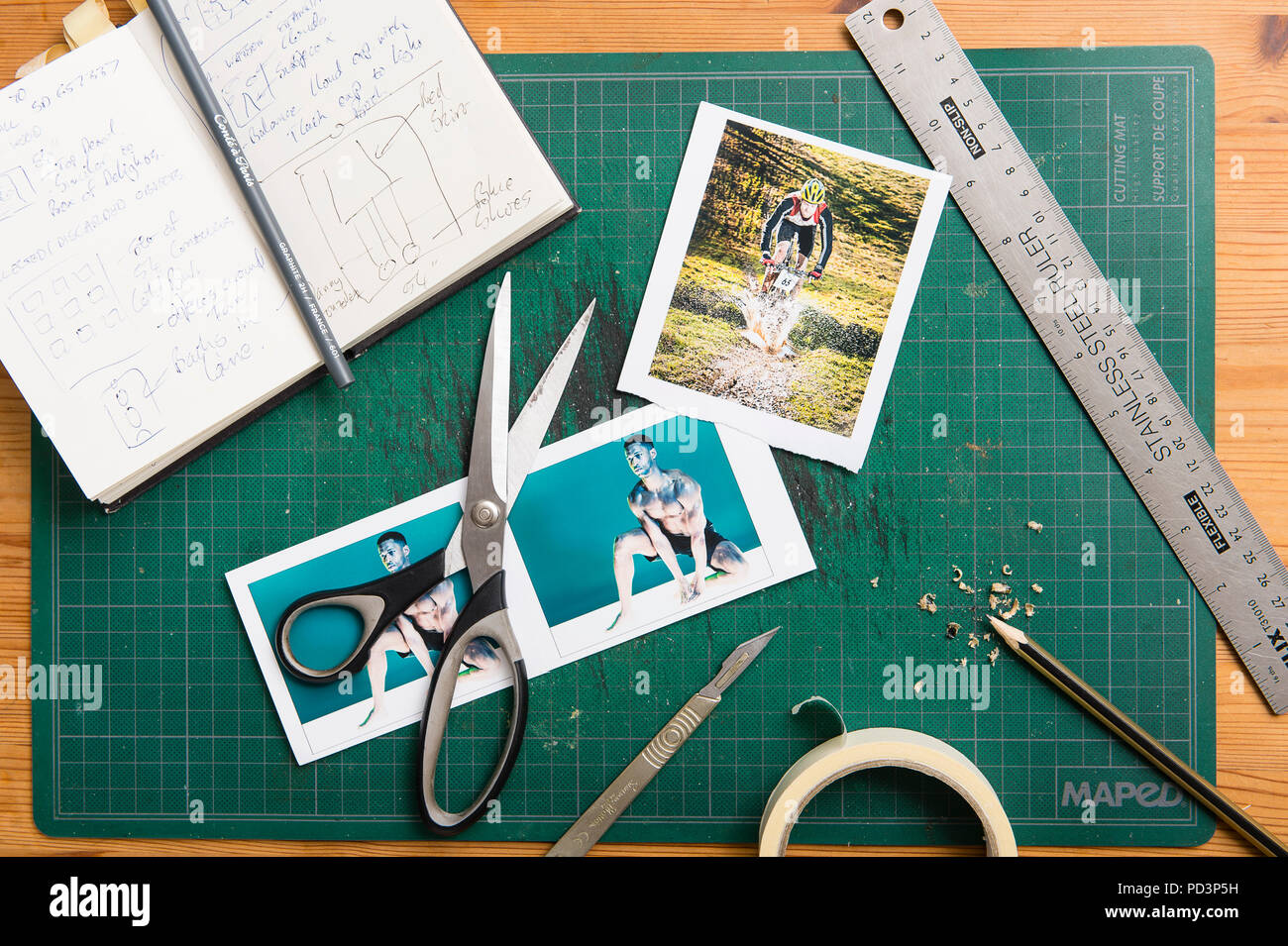 Top down view of cutting mat with sketchbook, scissors, tape, ruler