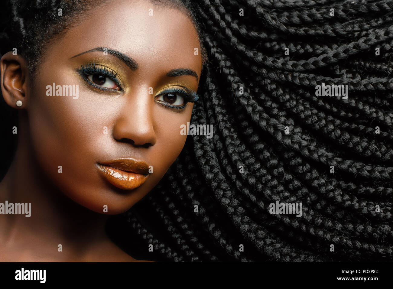 Extreme close up beauty portrait of young african woman showing long braided hair next to face. Stock Photo