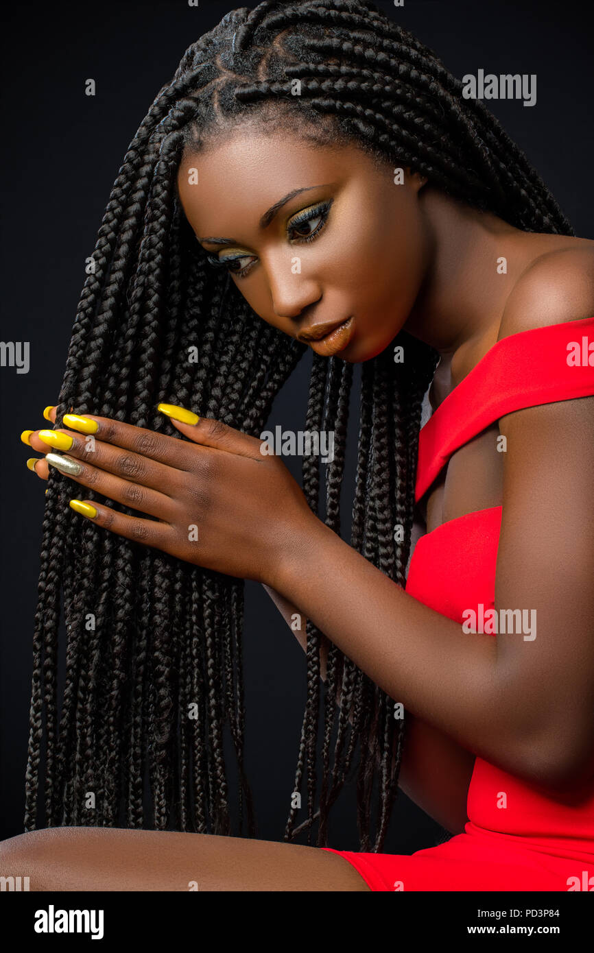 Close up studio portrait of sensual young african woman caressing long braided hair. Stock Photo