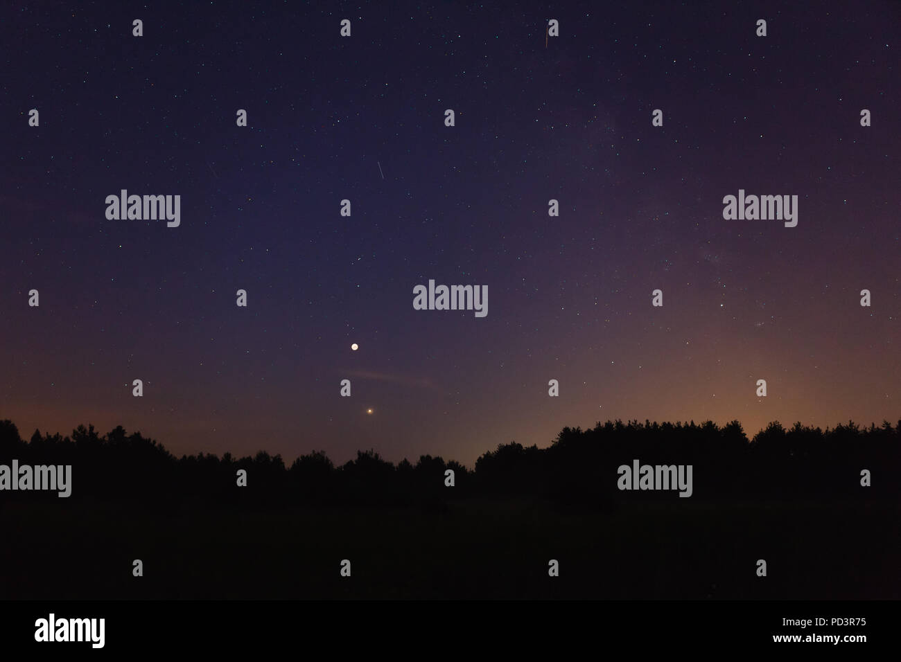 Night sky over forest, visible full eclispse of Moon, Mars in perigee, satellites and Milky Way Stock Photo