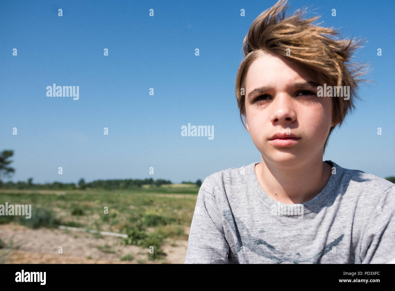 Teenage boy, flat countryside in background Stock Photo