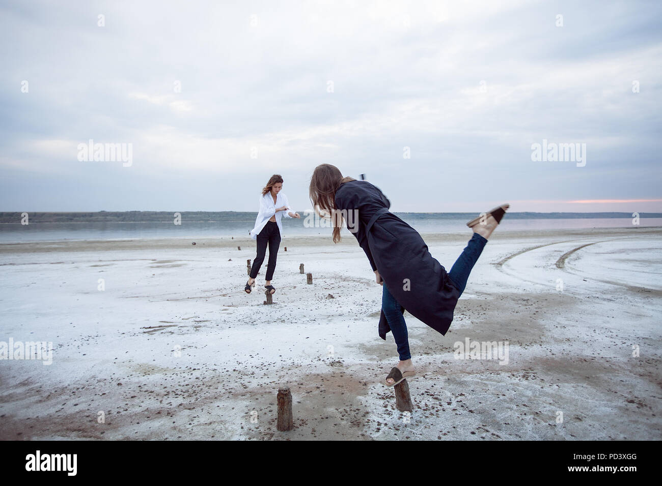 Women balancing on wooden stumps on beach, Odessa, Ukraine Stock Photo