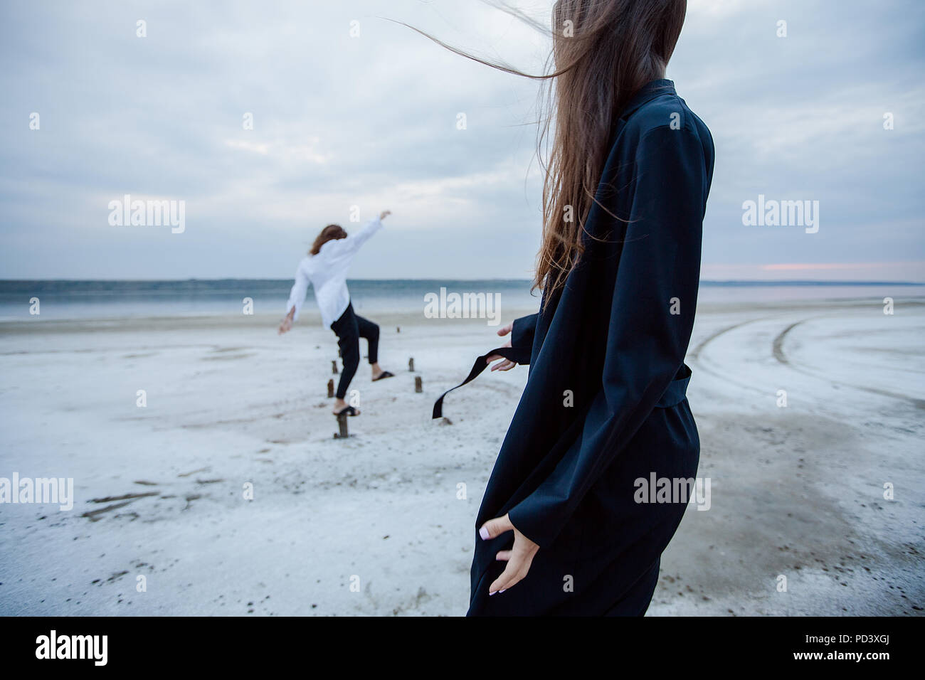 Women balancing on wooden stumps on beach, Odessa, Ukraine Stock Photo