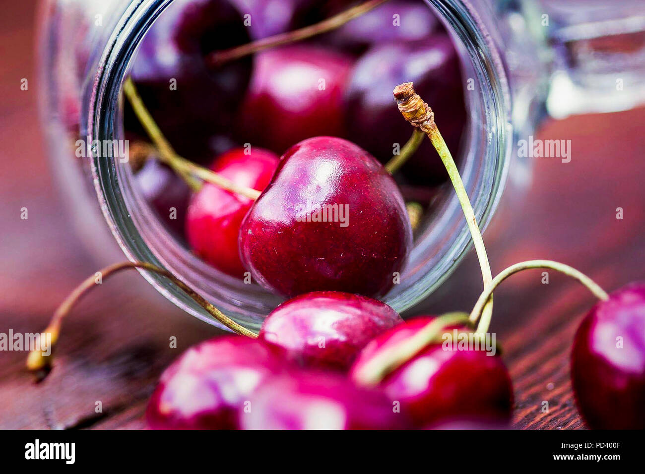 Fresh Cherries falling out of a glass jar Stock Photo