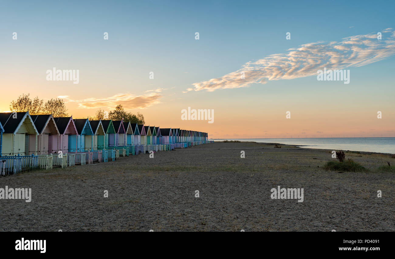 Attractive Beach huts at sunrise in summer on deserted West Mersey seaside resort beach in England Stock Photo