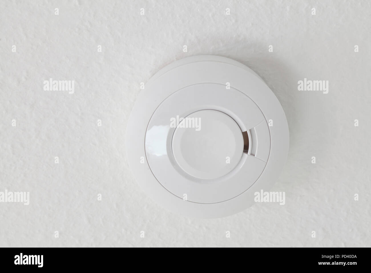 White smoke detector hangs on white ceiling Stock Photo - Alamy