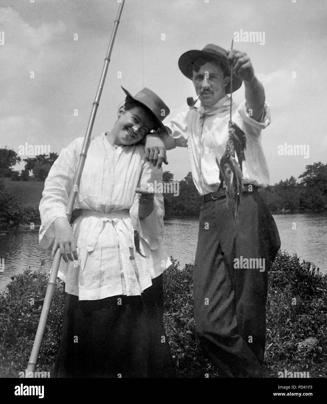 A young fishing couple show off their catch, ca. 1910. Stock Photo