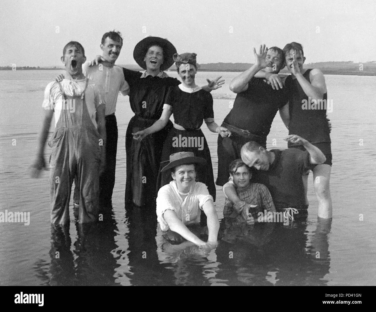 A group of young adults have fun and frolic while swimming in a lake, ca 1910. Stock Photo