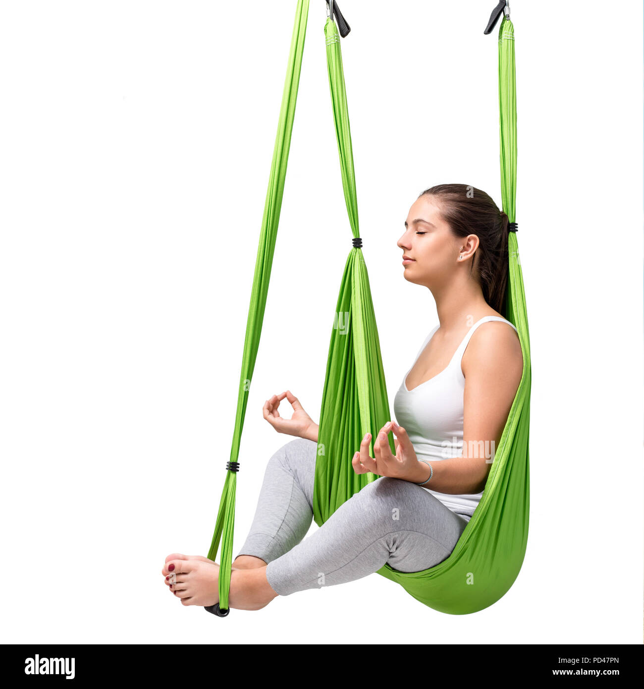 Portrait of young woman doing aerial yoga. Girl sitting with eyes closed in green antigravity yoga hammock isolated on white background. Stock Photo
