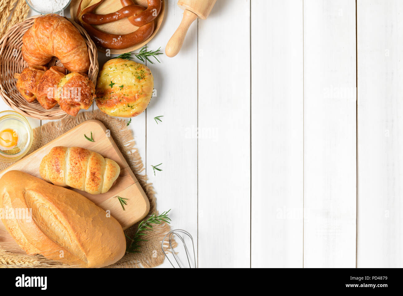Homemade breads or bun, croissant and bakery ingredients on white wood