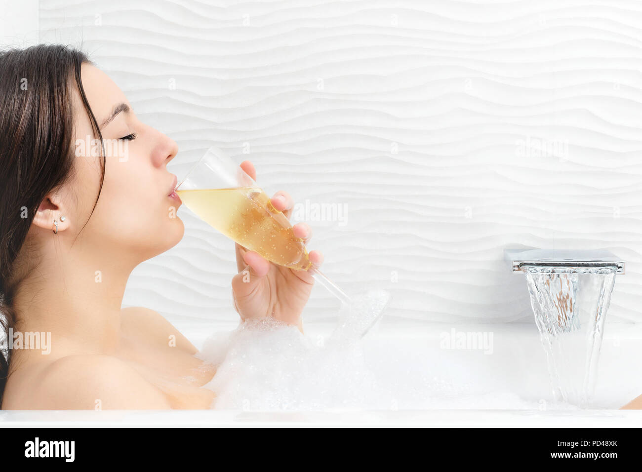Close up portrait of young woman relaxing in foam bath drinking champagne. Stock Photo
