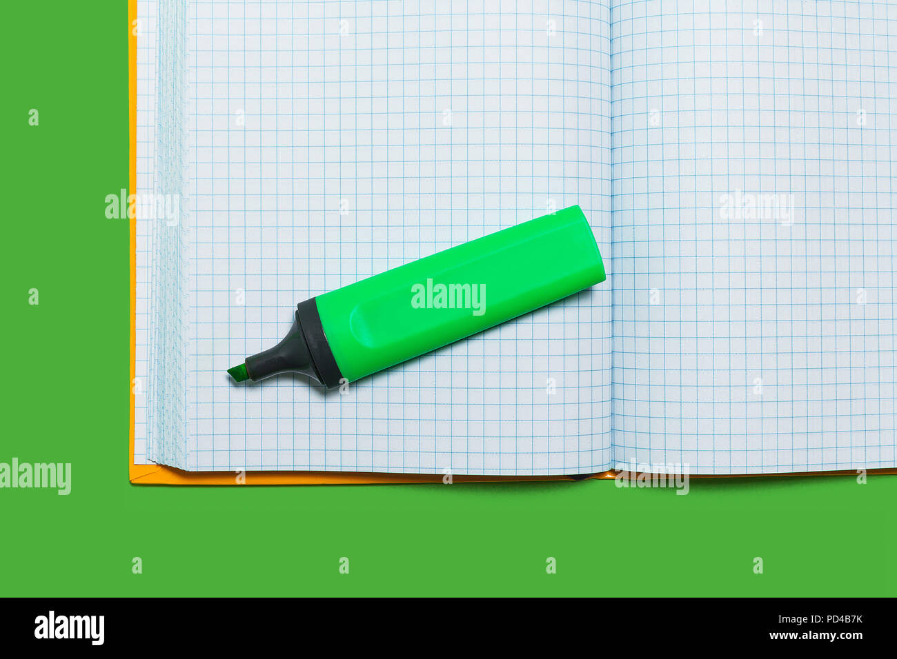 opened workbook and a marker on a green surface Stock Photo