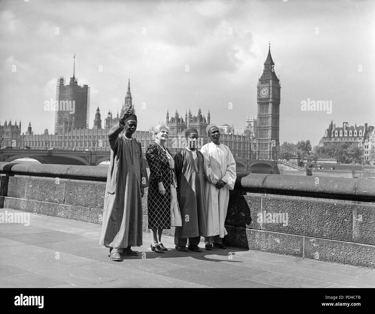 19th July 1950. London. England. Paramount Chiefs from Sierra Leone Jaia Kaikai, Kai Samba, and Alkali Inodu III, take a look at the view from the terrace of County Hall, during a visit to the headquarters of the London County Council. With the chiefs is Mrs. Helen C. Bentwich, Vice-Chairman of the Council. In the background can be seen the Houses of Parliament and Big Ben, across the river. The chiefs made the six week visit to Britain under the auspices of the British Council to see something of life in Britain. Stock Photo
