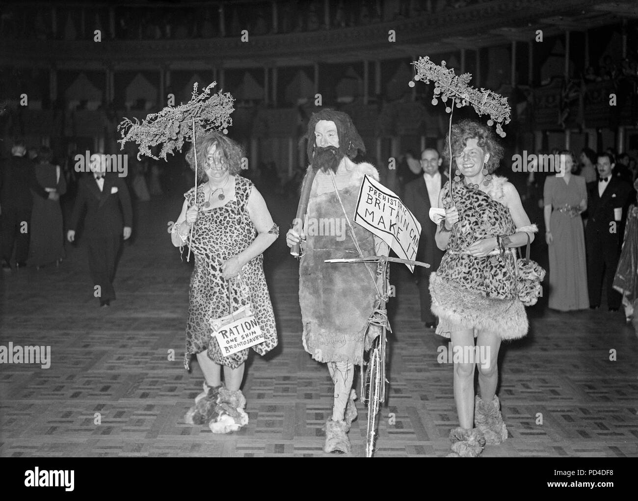 28th September 1946. Royal Albert Hall, London, England. A Five Arts Ball. The first full scale fancy dress ball since the end of the Second World War, took place in aid of the Royal Free Hospital. Photo shows 'As Prehistoric Britain Can Make It', a tableau carrying an illusion of the 'Britain Can Make It' campaign of the time. Left to right, Mr. and Mrs. J. W. Fiske, and Mrs. R. P. Crampton. Stock Photo