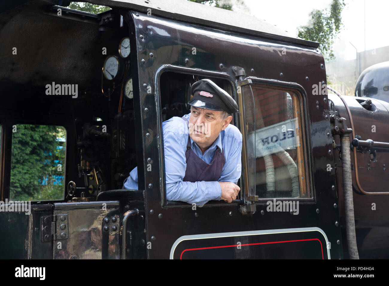 Engine driver on the footplate of No.78018 British Railways Standard Class 2 steam locomotive and looking out of the cab Stock Photo