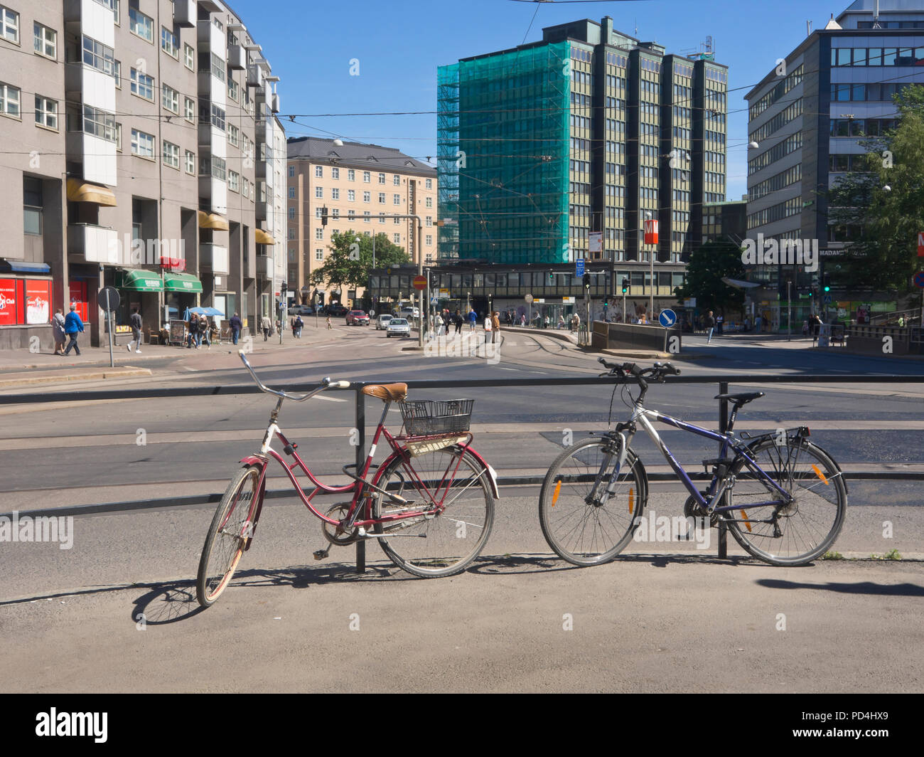 His and hers bikes locked to a railing in an intersection by the Sörnäinen  tram stop in  Helsinki Finland Stock Photo