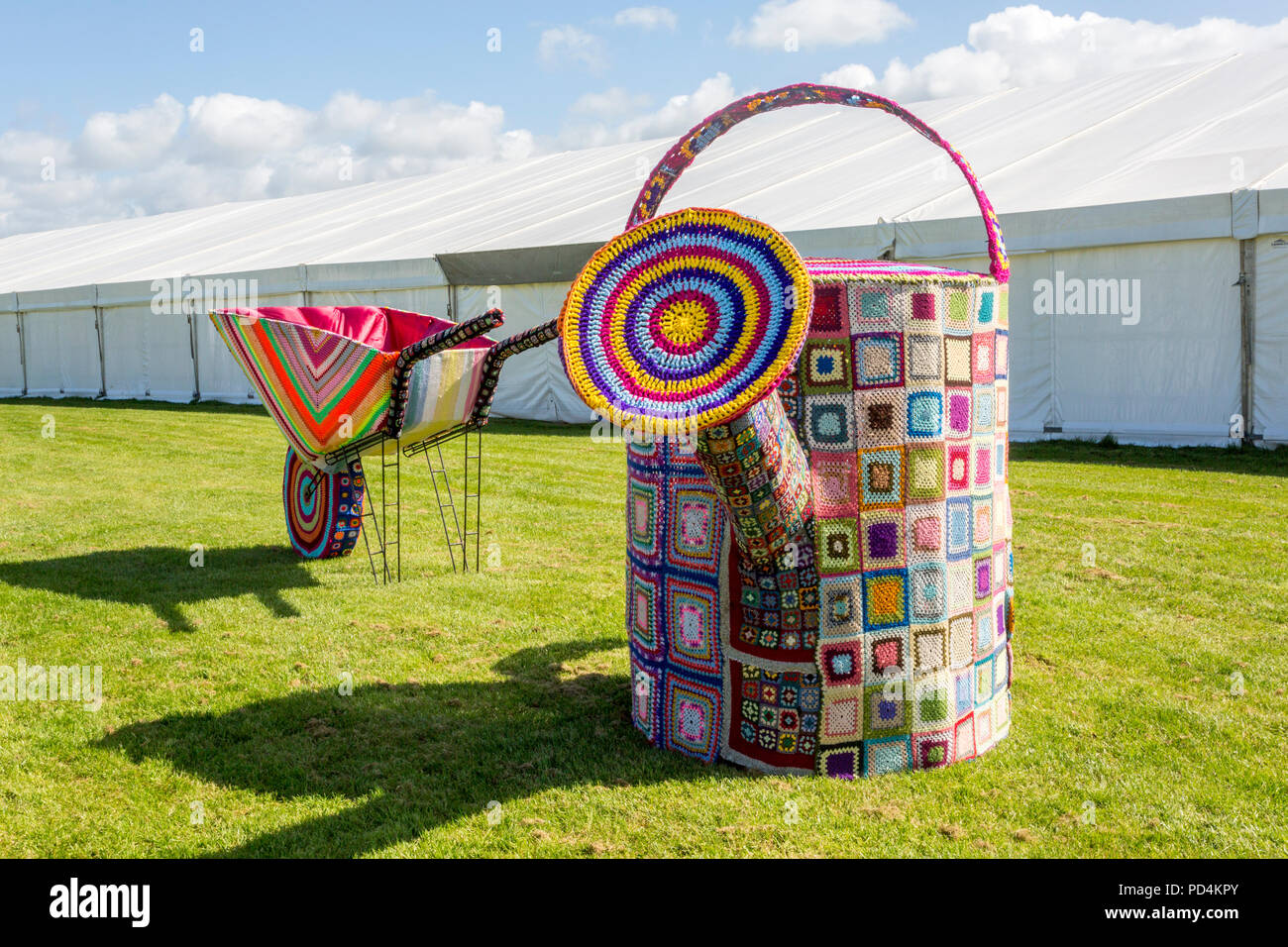 A huge knitted wheelbarrow and watering can at the 2018 Malvern RHS Spring Show, Worcestershire, England, UK Stock Photo