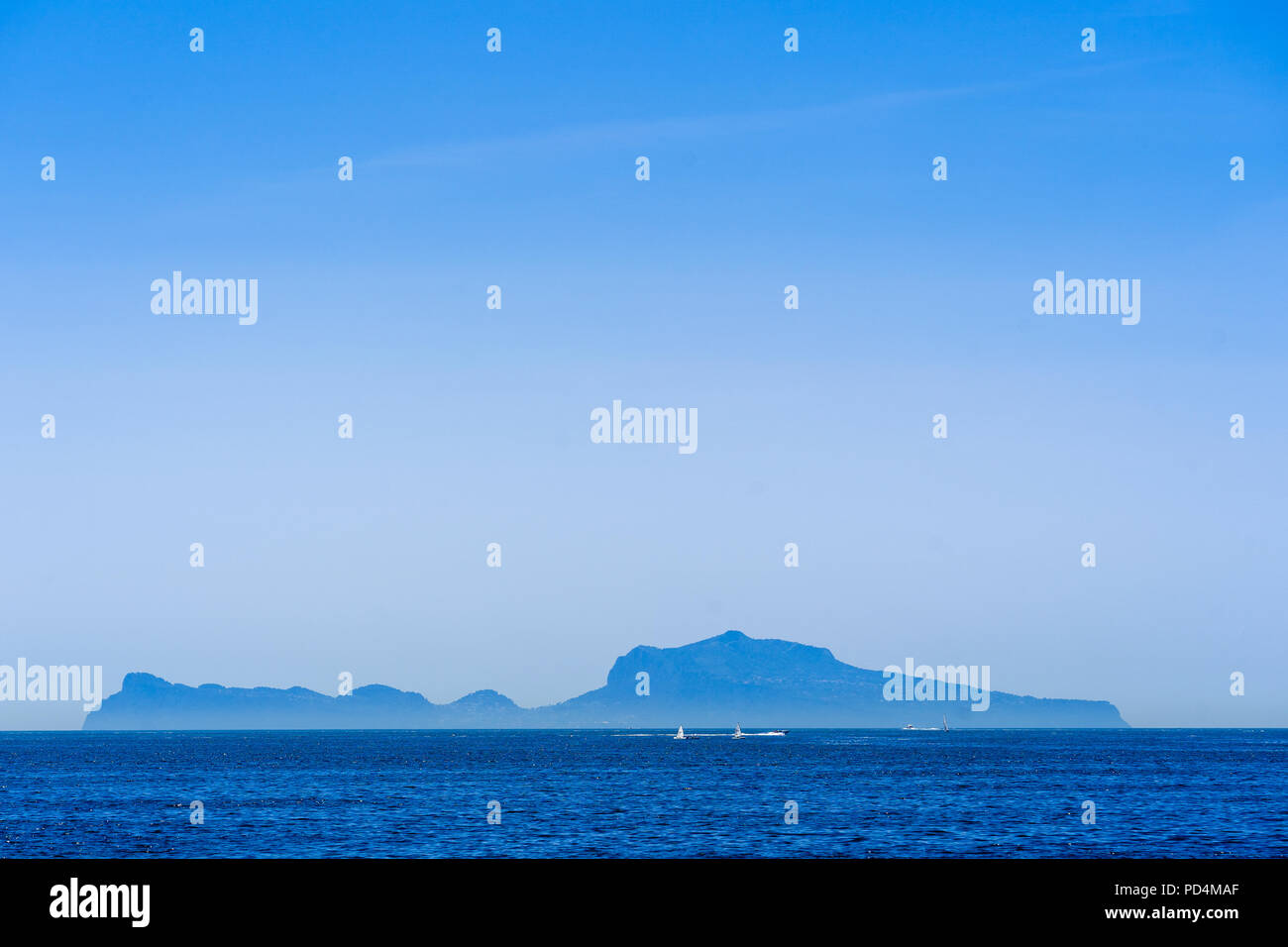 The island Capri seen behind boats from the waterfront in Naples, Italy Stock Photo