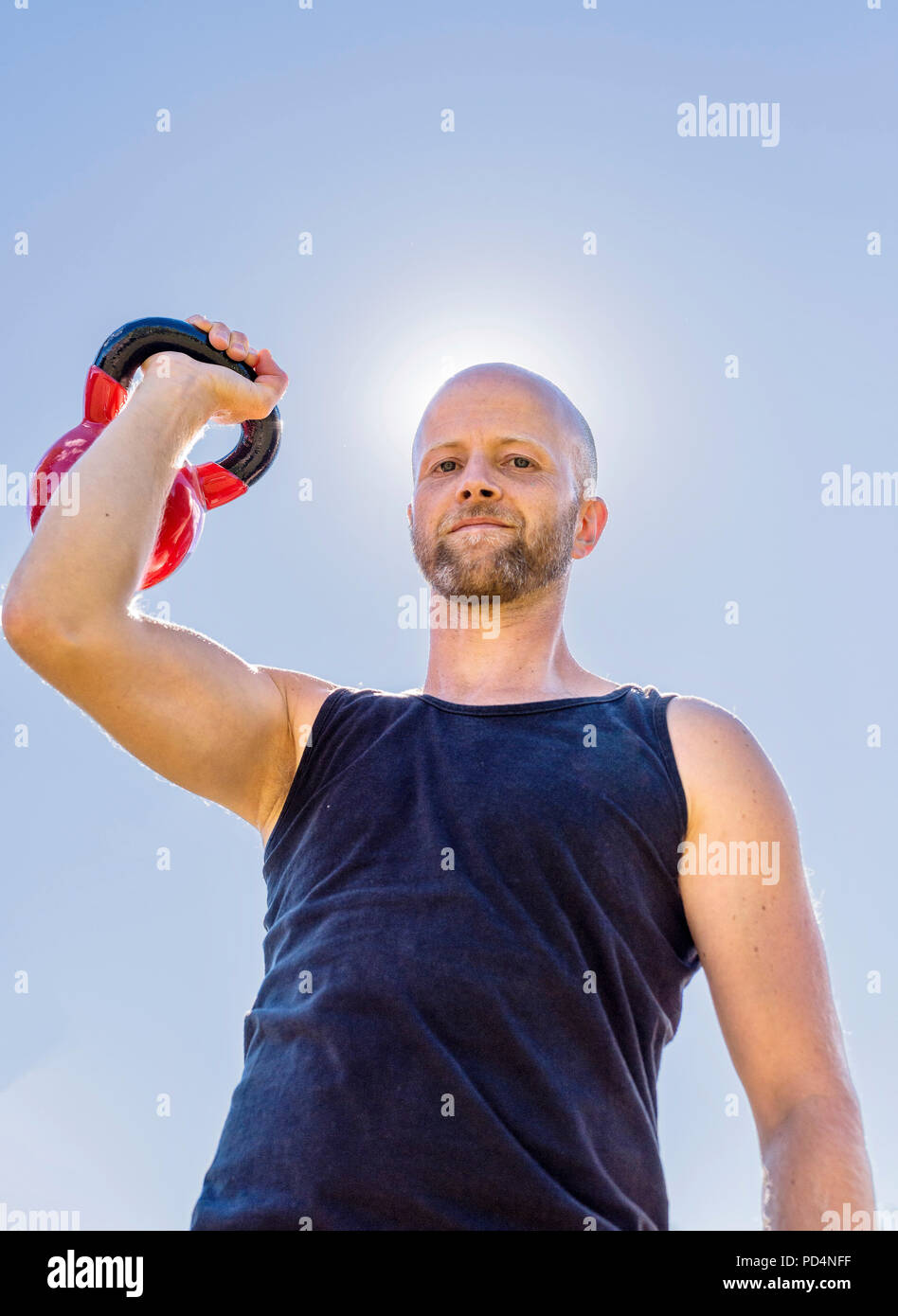A young man training with Kettle Bells outdoors Stock Photo