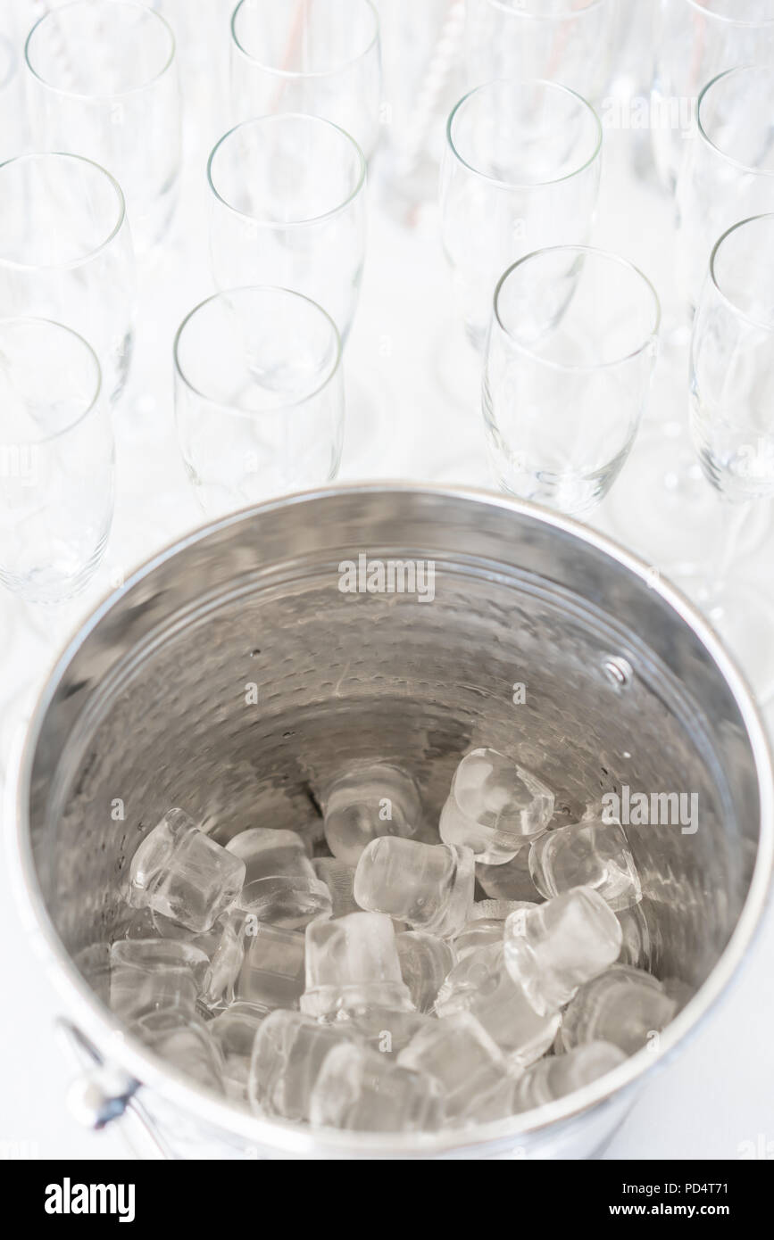 A metal ice bucket with full of crushed ice and stainless scoop for