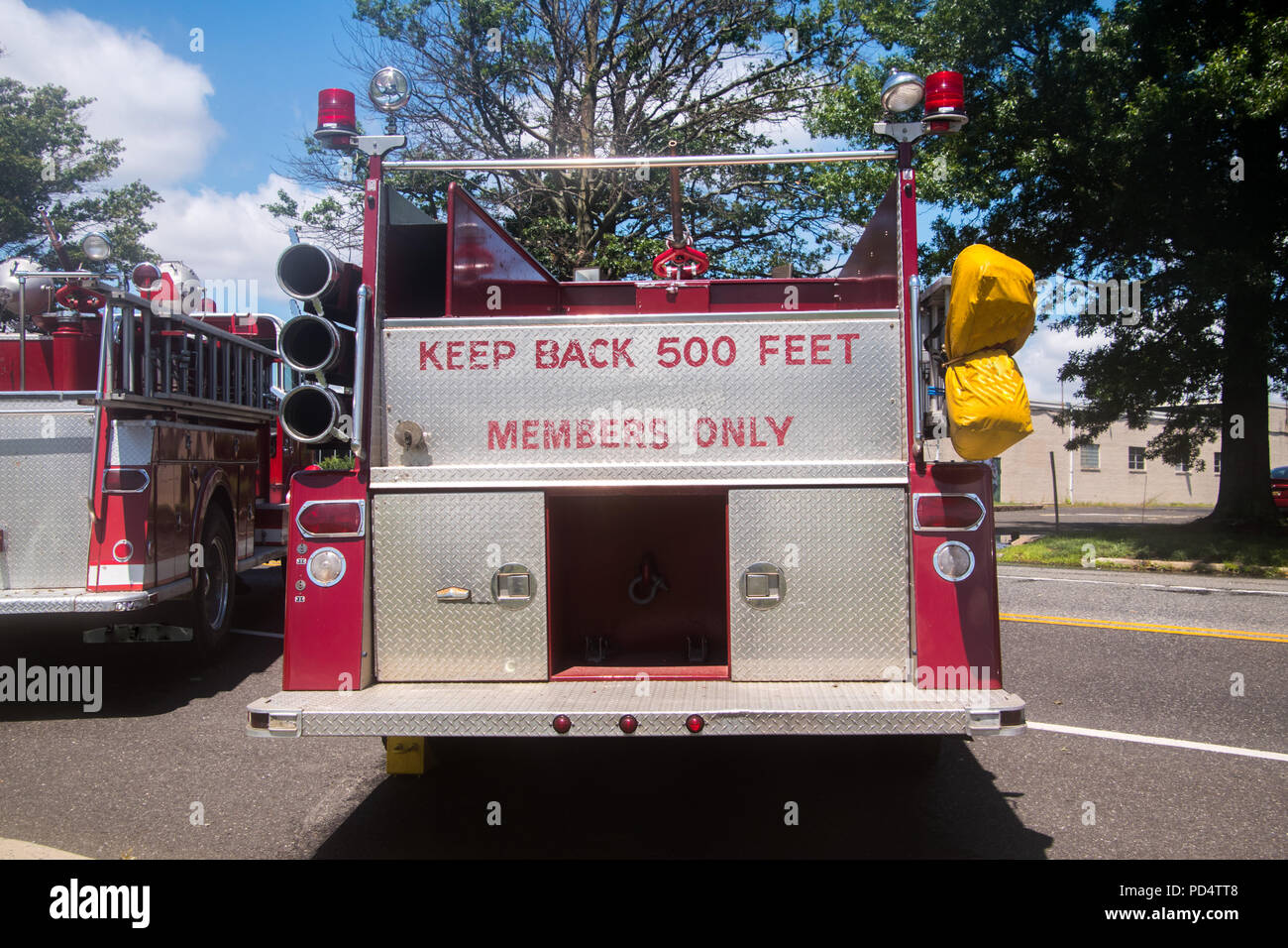 Back of red fire truck with the words Keep Back 500 Feet and Members Only panted in red on the chrome in the back Stock Photo