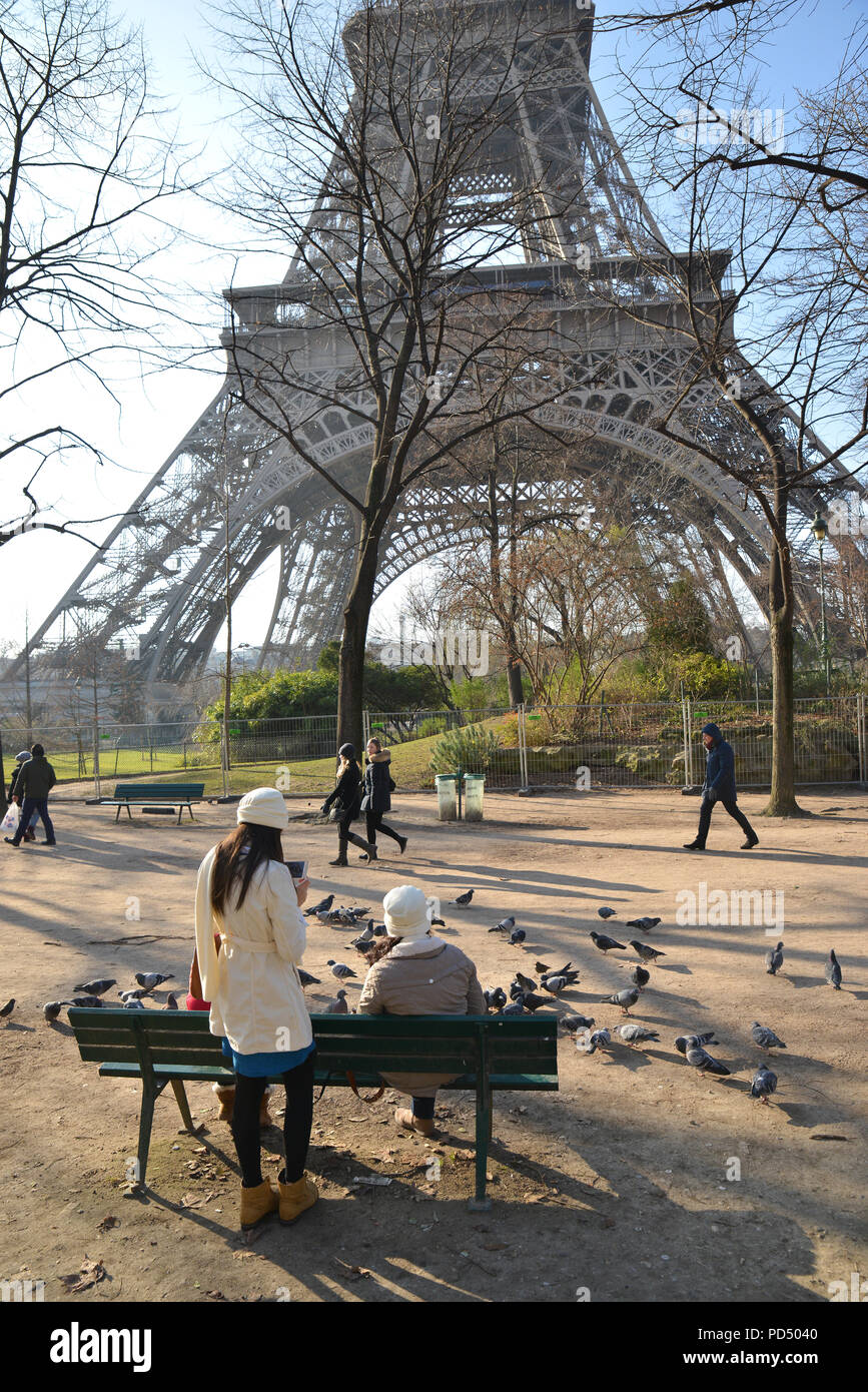 Mother and daughters feeding pigeons at a park near the Eiffel Tower in Paris Stock Photo