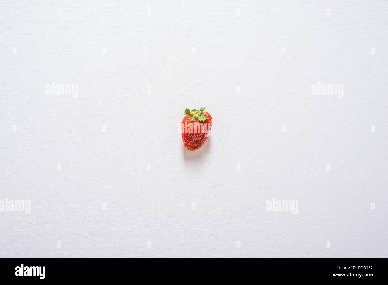 one strawberry fruit on white wood table background Stock Photo - Alamy