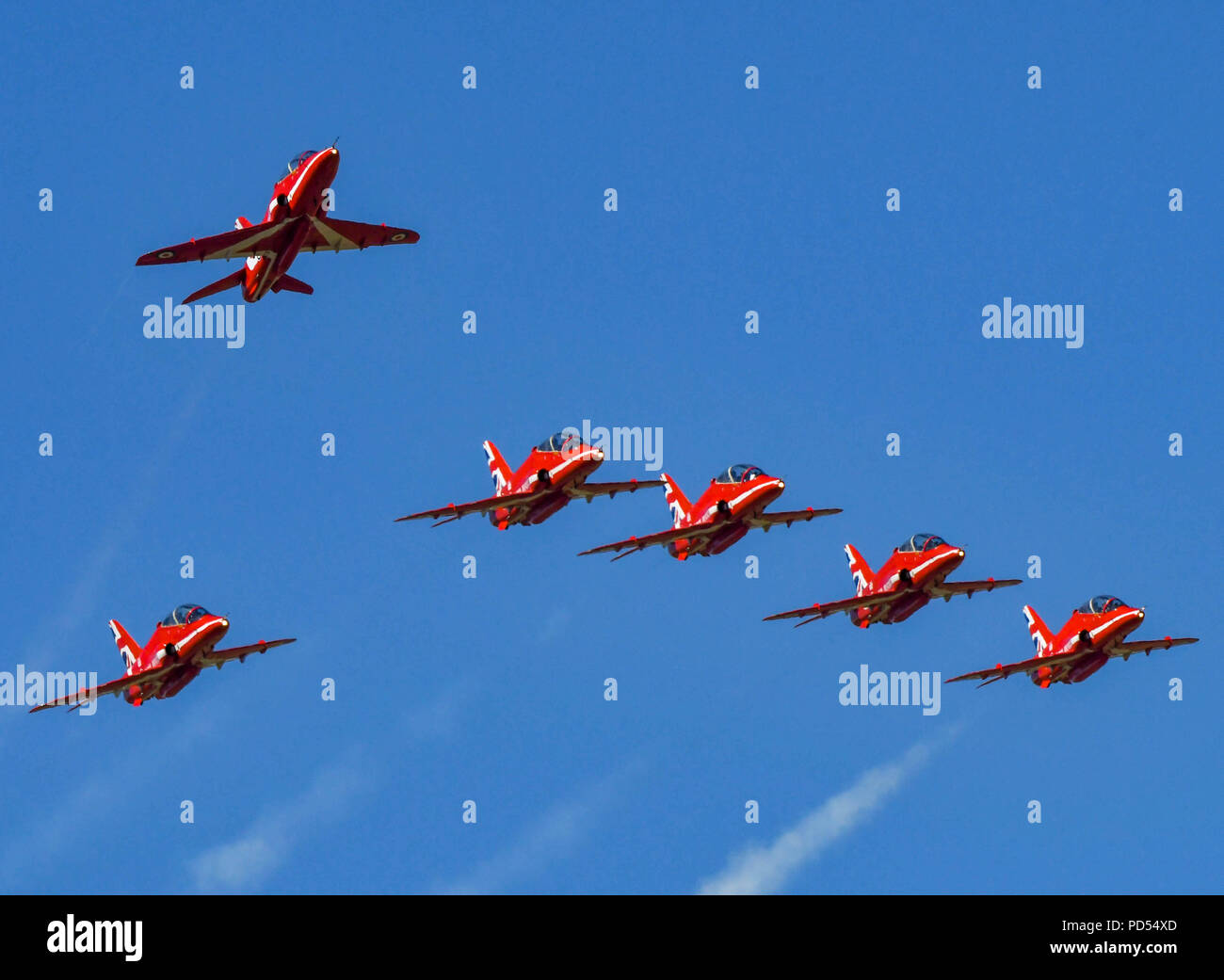 Six Hawk jets of the Royal Air Force Aerobatic Team, the Red Arrows, flying in formation over Cardiff wales Airport with the Team Leader breaking away Stock Photo