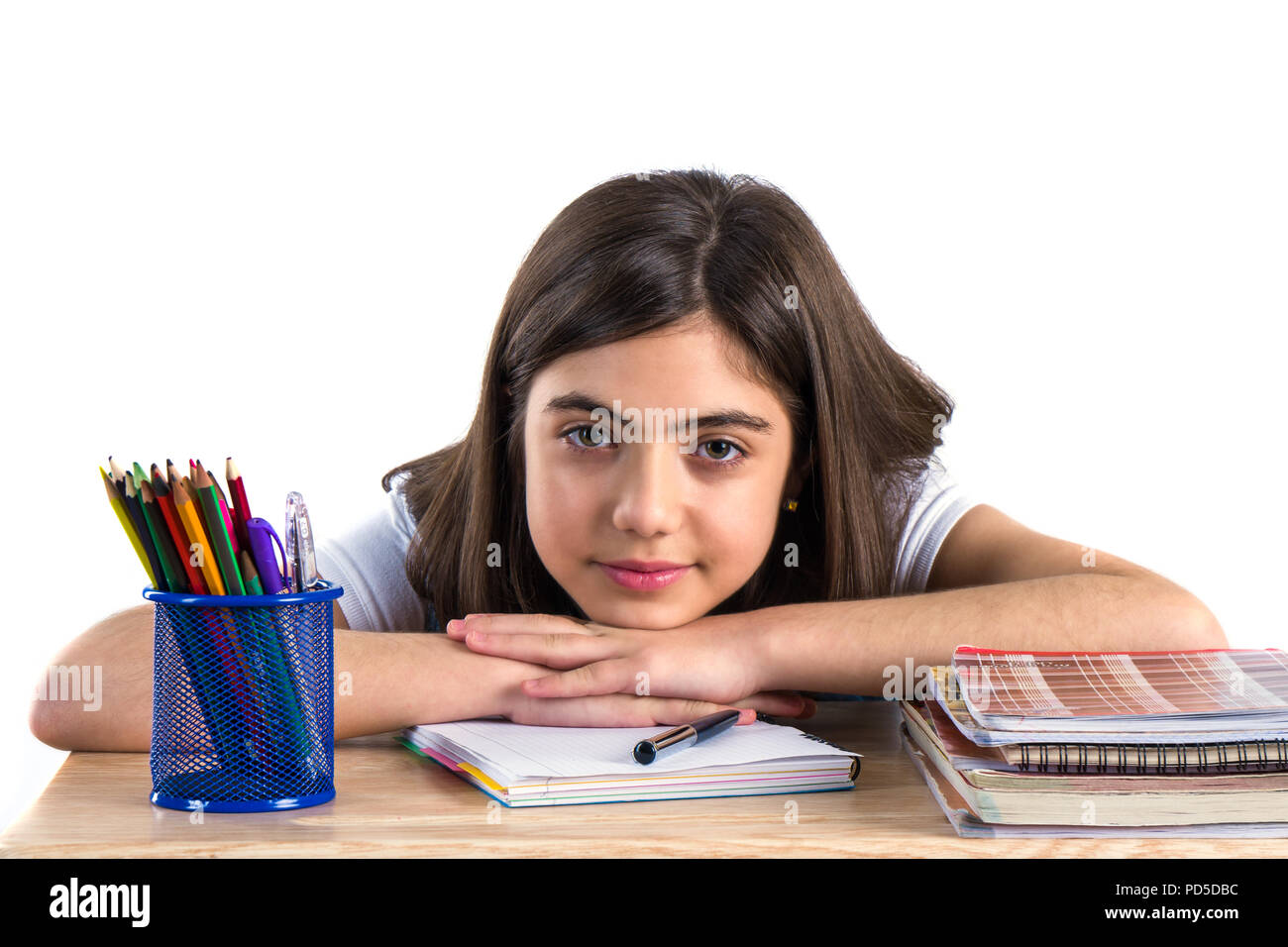 A beautiful school girl sits at the desk and thinking. White background ...