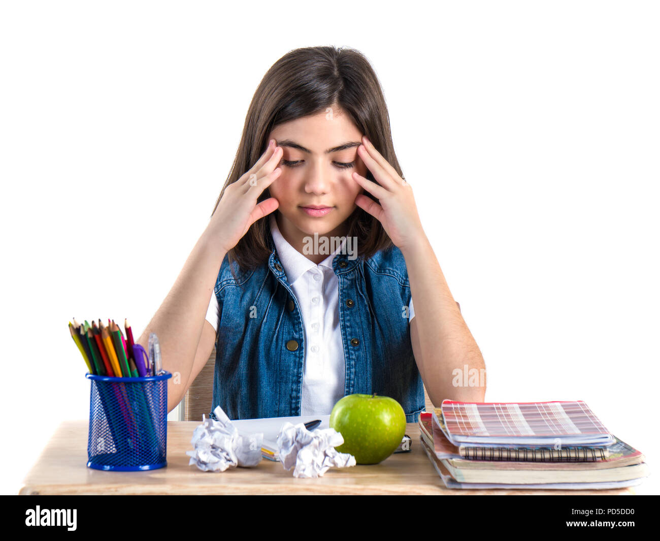 A beautiful school girl sits at the desk with apple and thinking. White ...