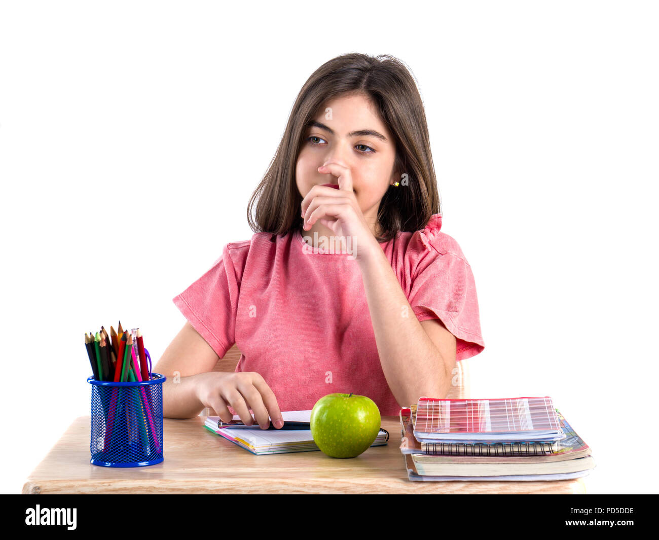 A beautiful school girl sits at the desk with apple and thinking. White ...