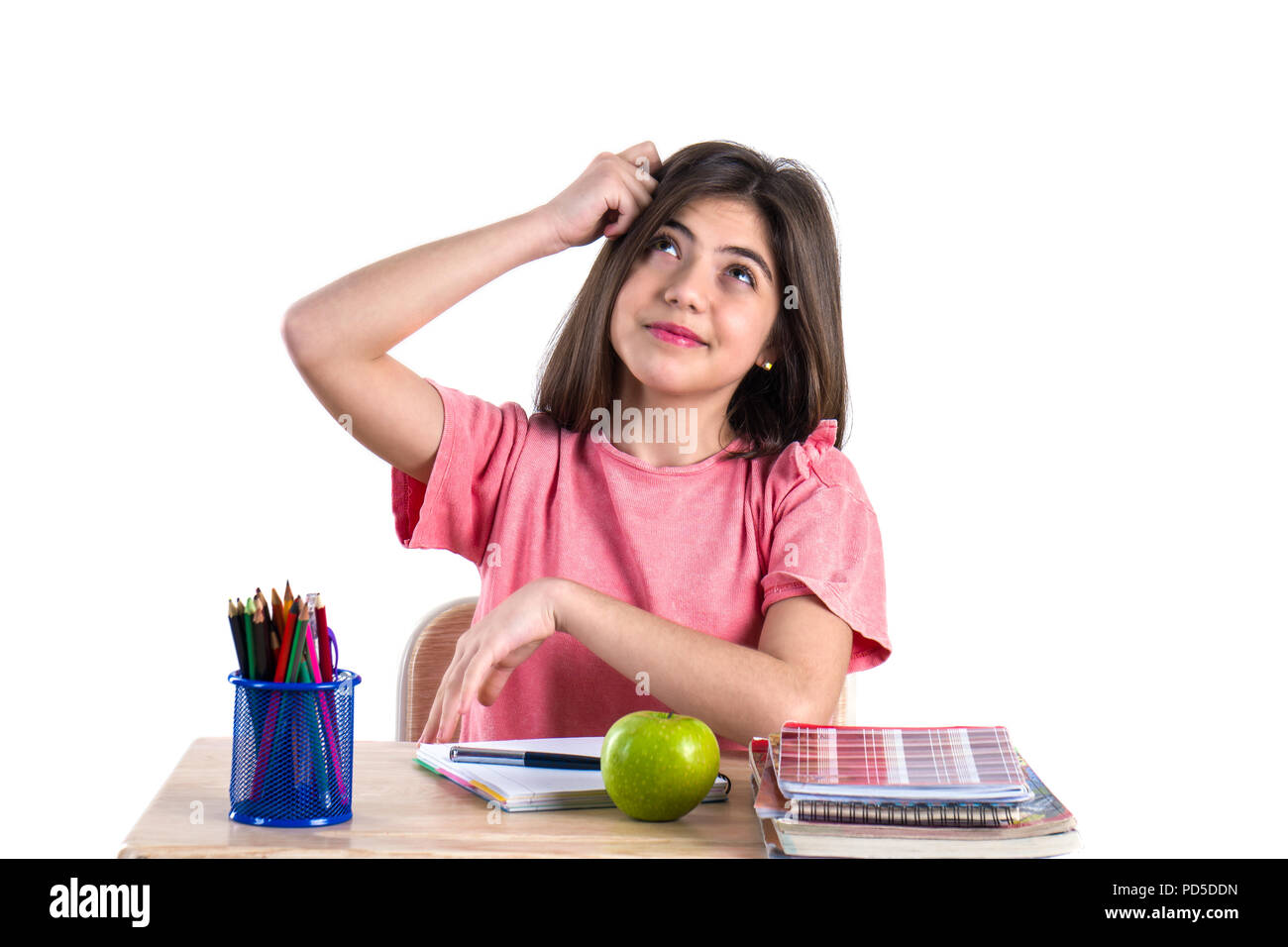 A beautiful school girl sits at the desk with apple and thinking. White ...