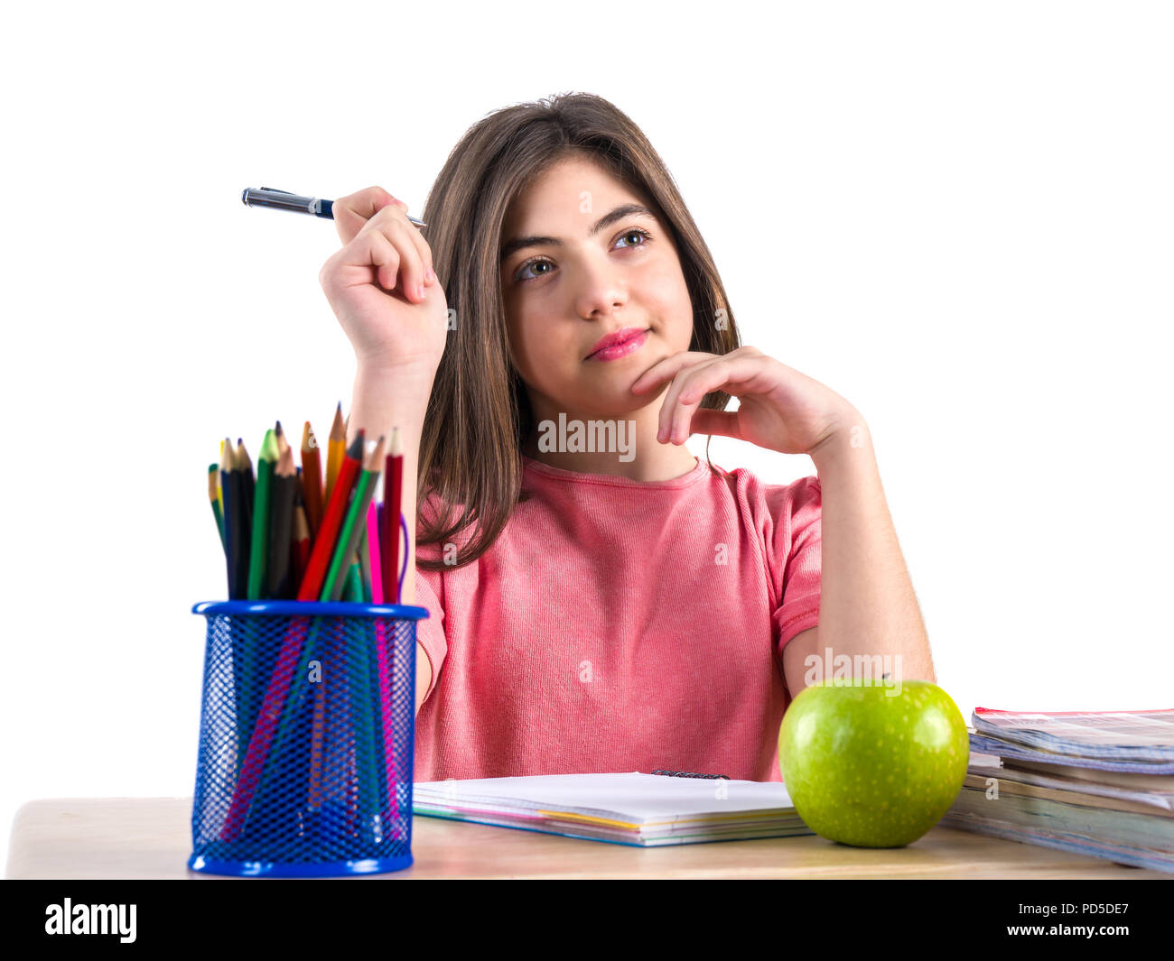 A beautiful school girl sits at the desk with apple and thinking. White ...