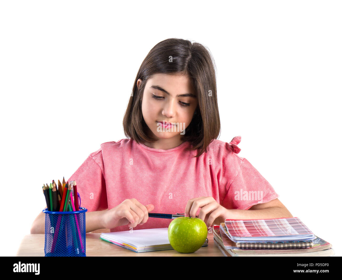 A beautiful school girl sits at the desk with apple and thinking. White ...