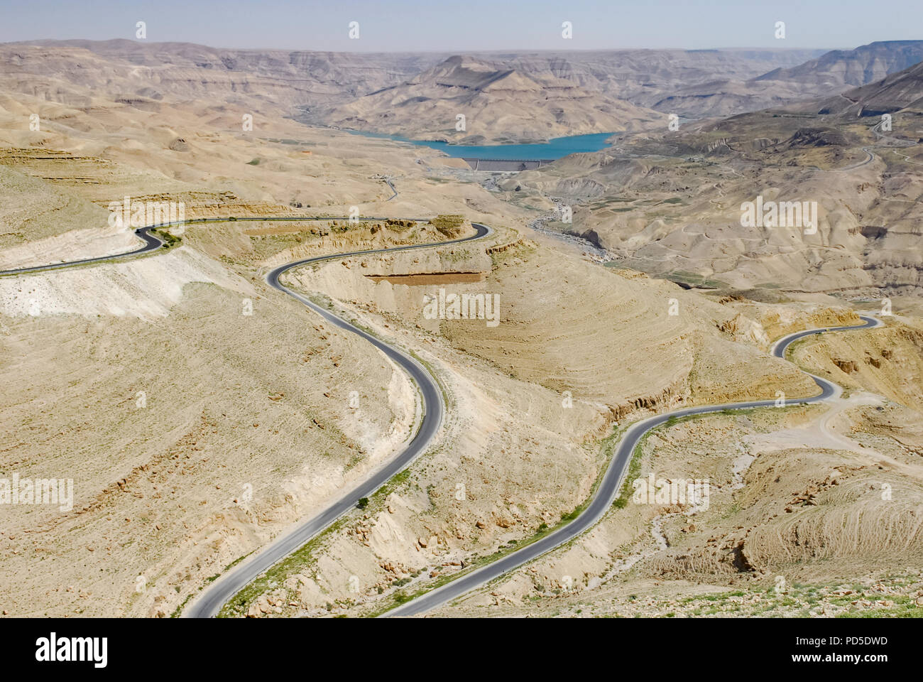 Winding asphalt road through desert and valley with a blue lake in the background Stock Photo