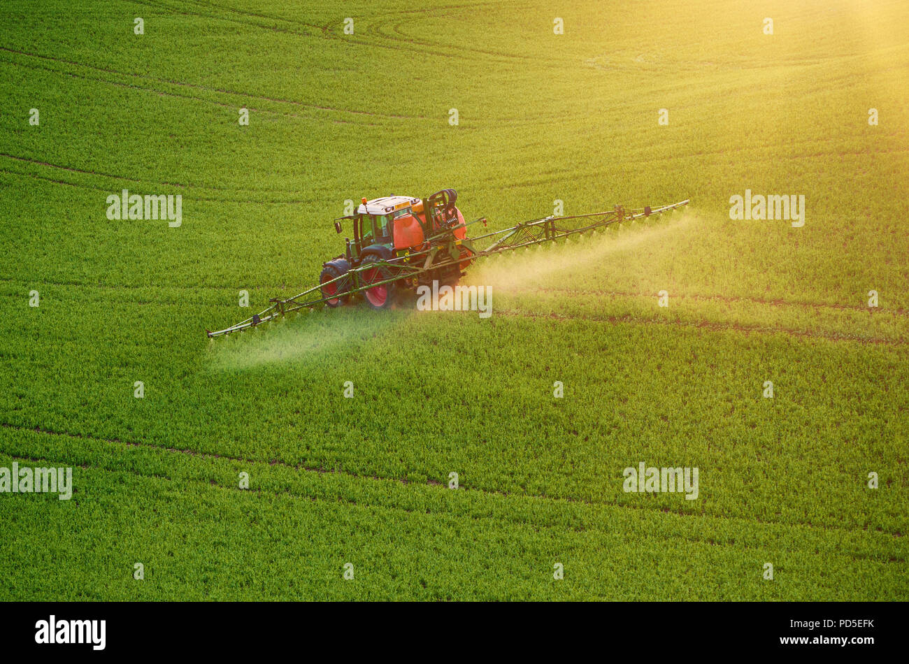 Farm machinery spraying insecticide to the green field, agricultural natural seasonal spring background Stock Photo