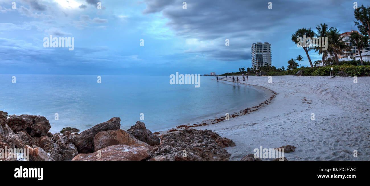 Rain pours from dark clouds over Clam Pass Beach in Naples, Florida around sunset. Stock Photo