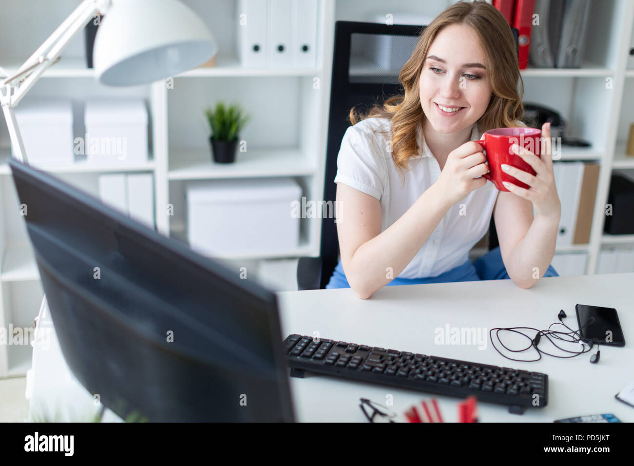 Beautiful young girl working with computer in office. The girl has a ...