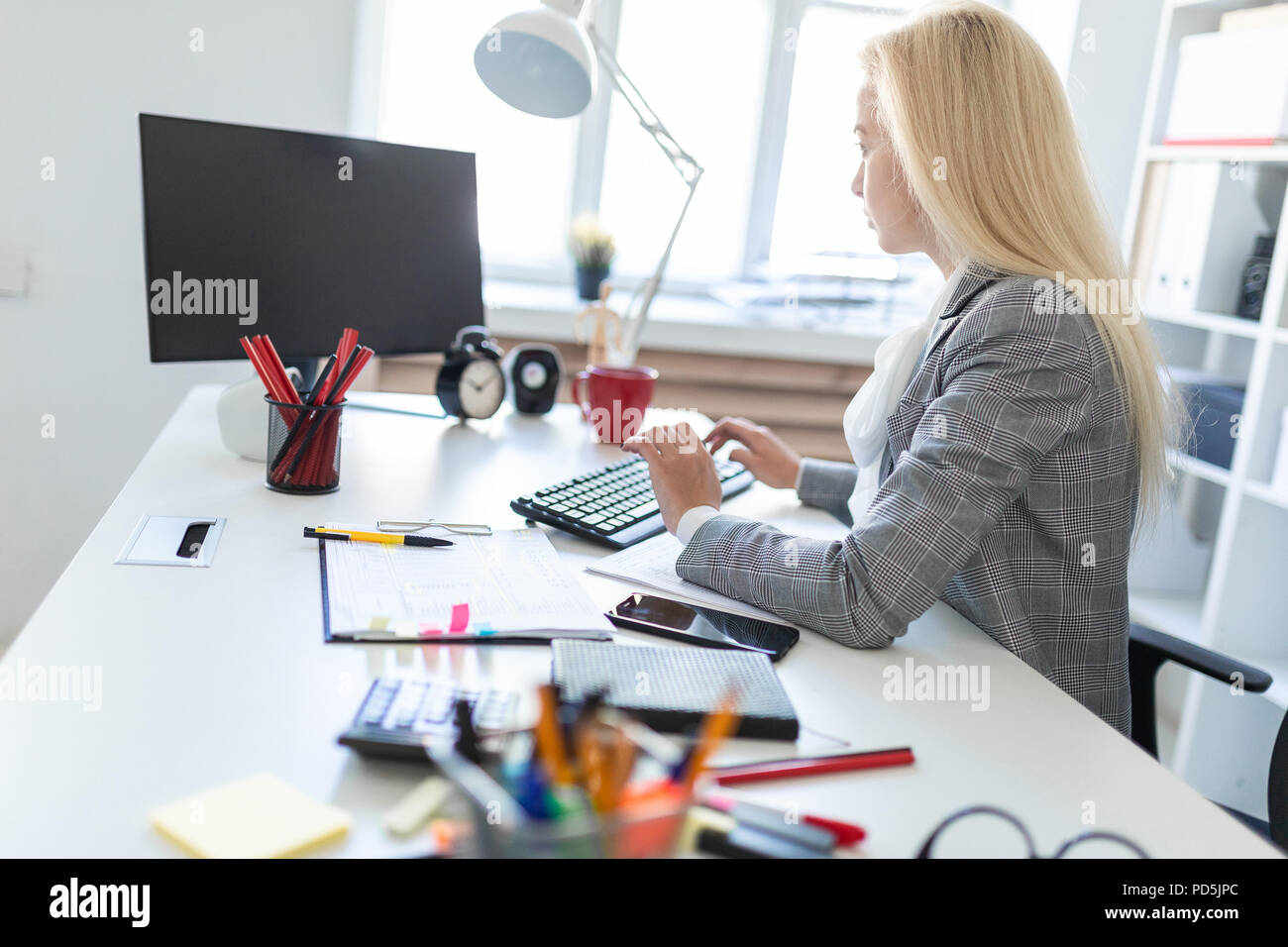 Young girl in office working with computer and documents Stock Photo ...