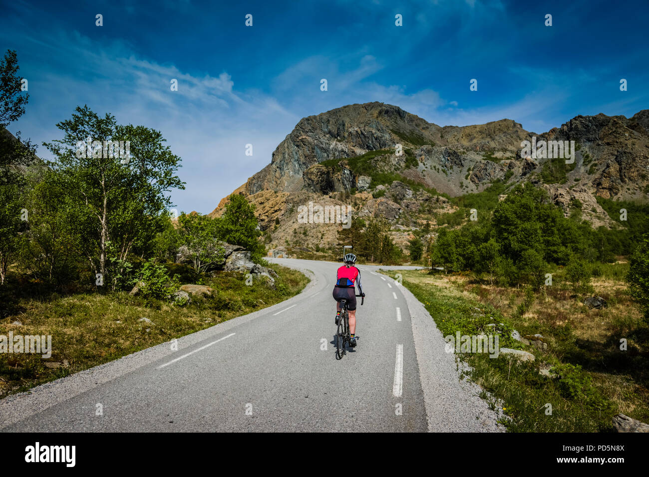 Female cyclist exploring Leka island, Norway. Stock Photo