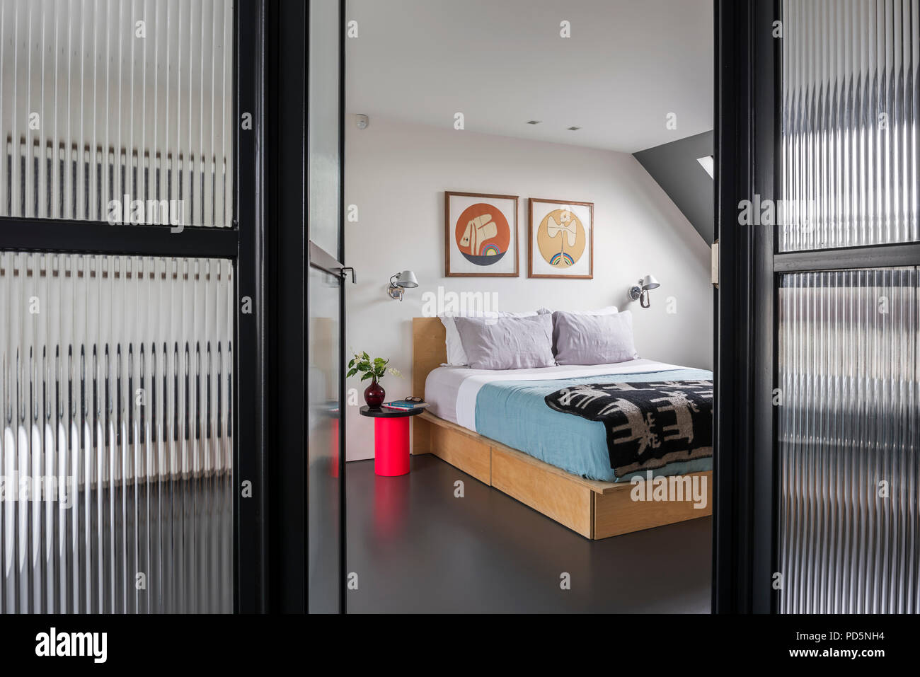 View through corrugated style glass wall into minimal style bedroom Stock Photo