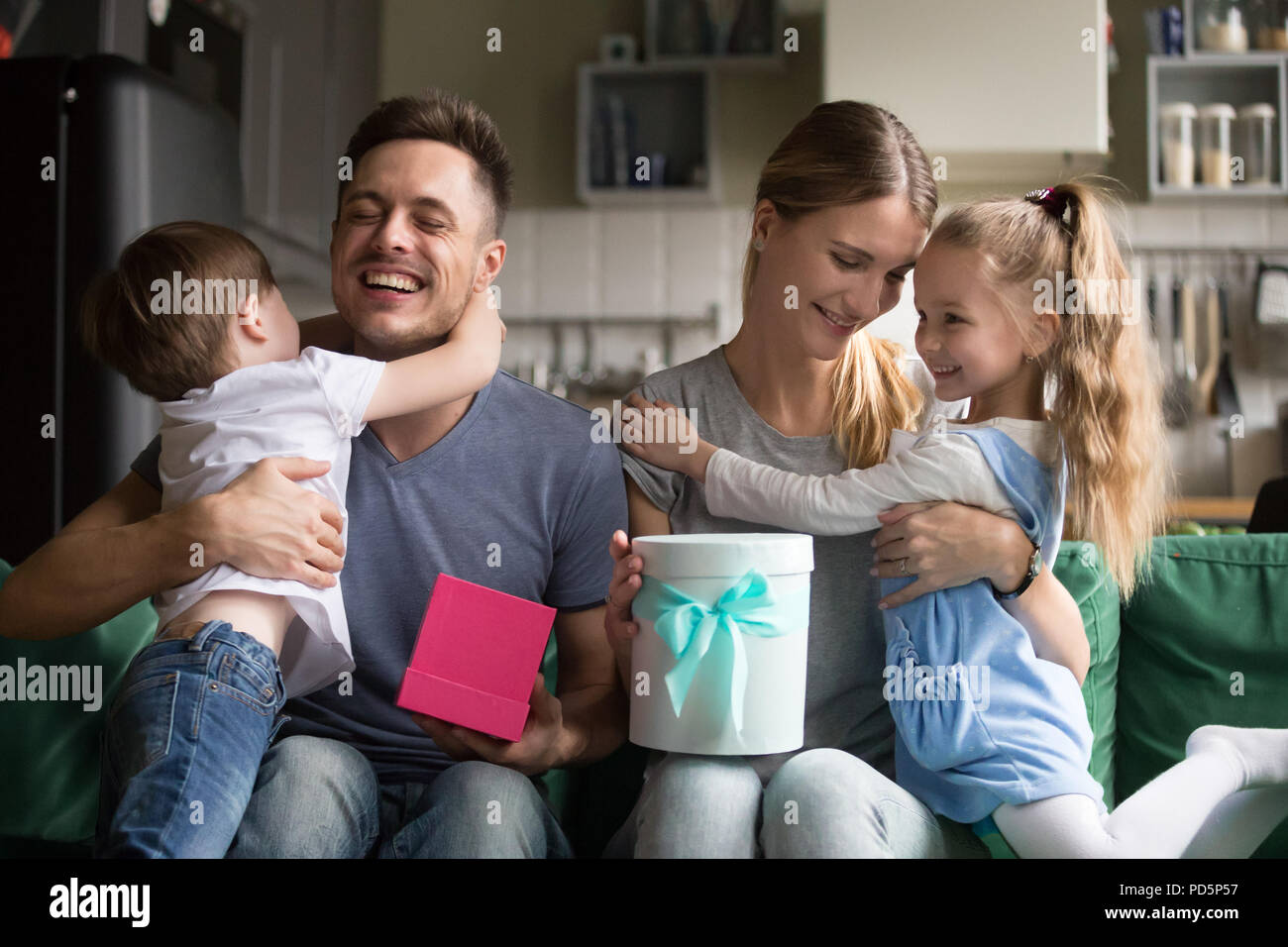 Happy mom and dad embracing kids thanking for gift boxes Stock Photo ...