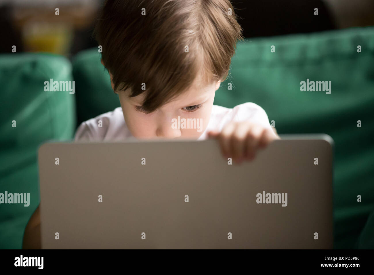 Curious kid boy secretly watching forbidden censored content on  Stock Photo